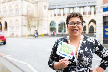 Healthwatch staff member holding an It Starts With You sign to promote the campain