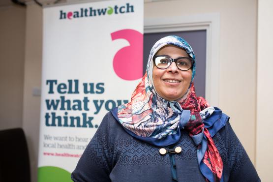 Healthwatch Volunteer in  front of banner