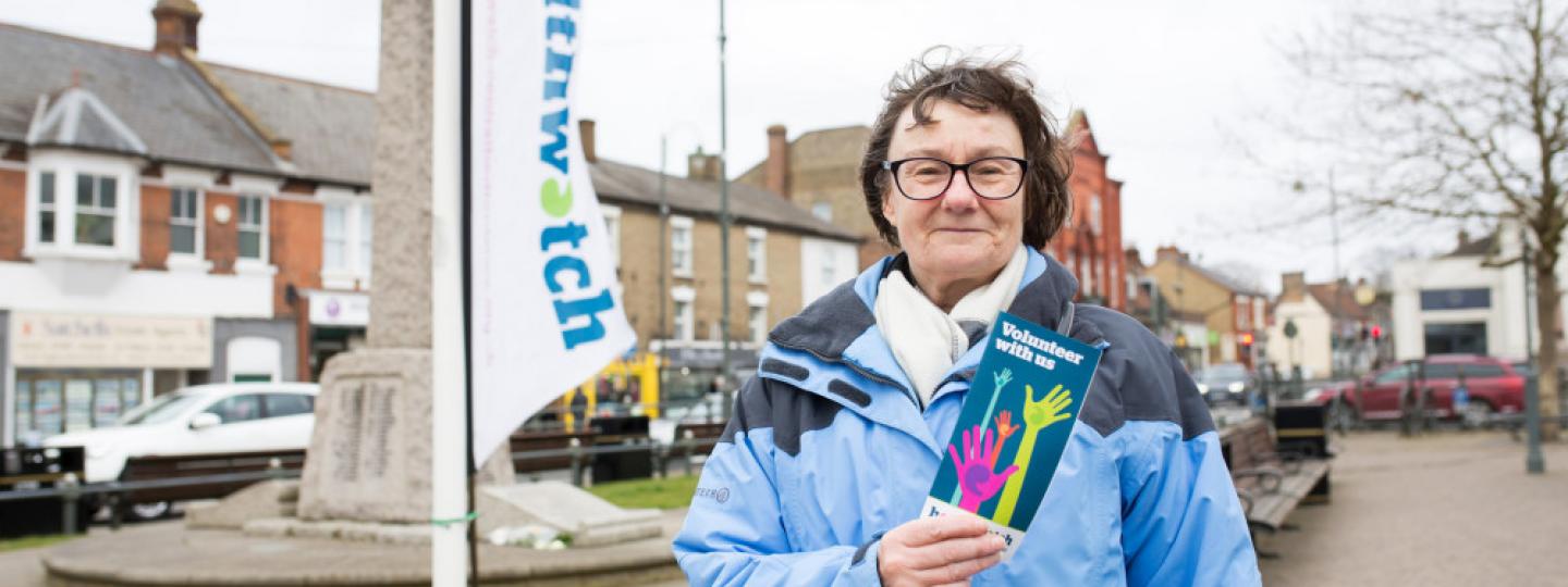 Volunteer holding Healthwatch leaflet by banner 