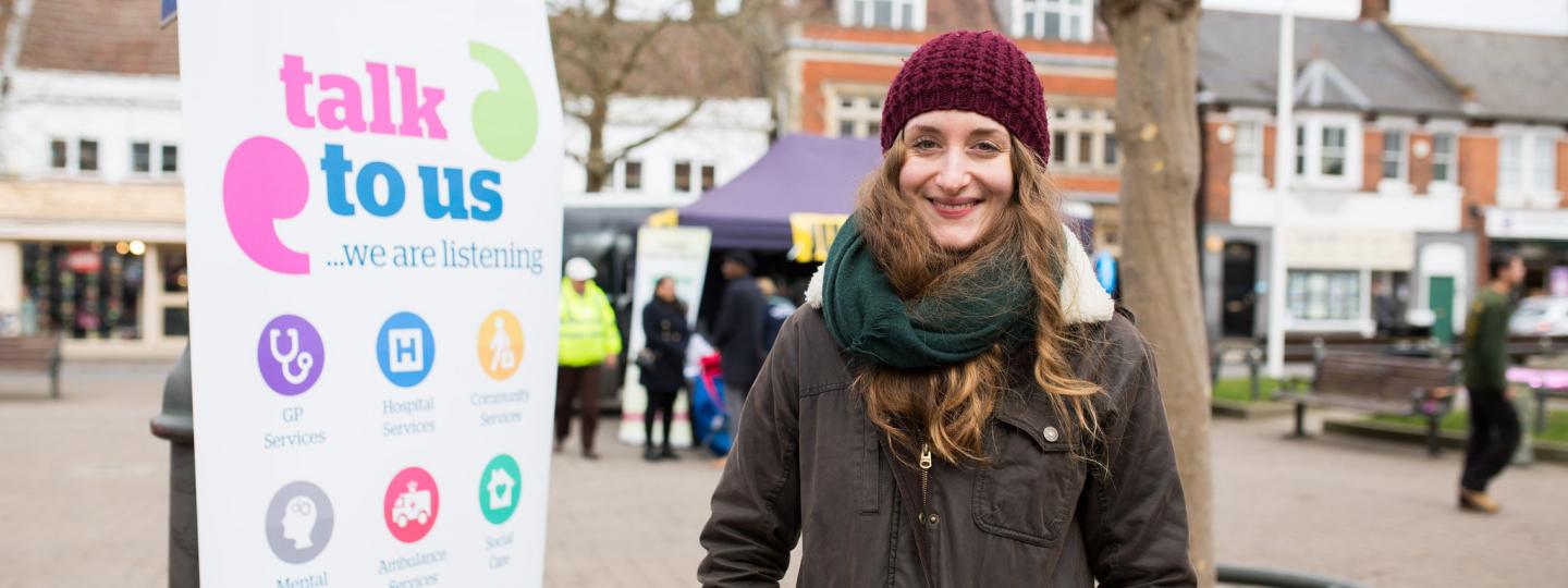 Young lady standing in front of healthwatch banner